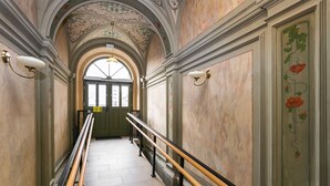 A hallway with ornate ceiling and walls, a handrail, and a door at the end. - City of The Kings Arianska Garden (Kraków)