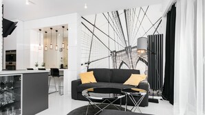 A modern living room with a black sofa, two black coffee tables, and a large abstract wall art piece. - City of The Kings Arianska Garden (Kraków)