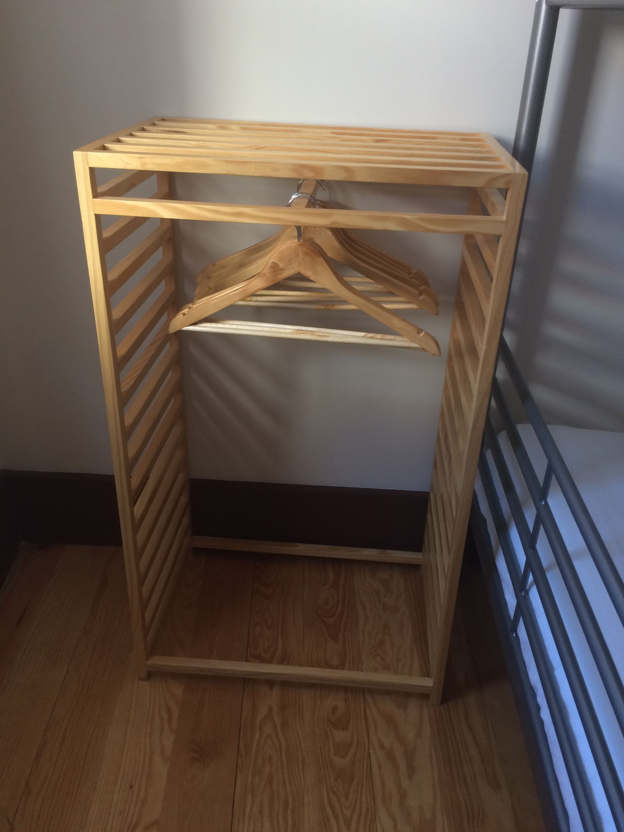 Ein Holzschrank mit Kleiderstange und Ablagefläche.