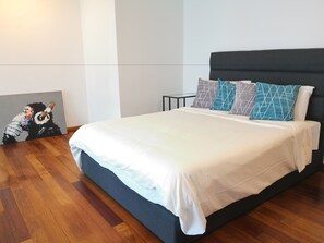 A modern bedroom with a large bed, dark headboard, and geometric patterned pillows.