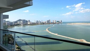A high-rise building with a view of a coastal cityscape, including a marina and a distant mountain range. - Casa Duplex at Sunrise Gurney Seaview (George Town)
