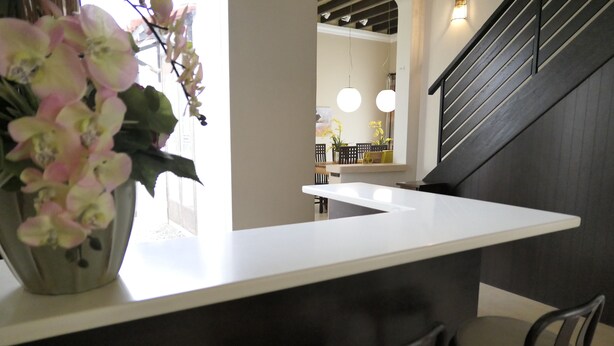 A modern kitchen with a white countertop, two chairs, and a vase of flowers. - Gurney 4 Plus 1 Bali Style Tranquil Villa (George Town)