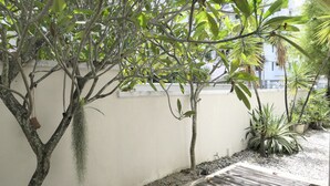A small outdoor area with a white wall, a wooden bench, and various potted plants. - Gurney 4 Plus 1 Bali Style Tranquil Villa (George Town)