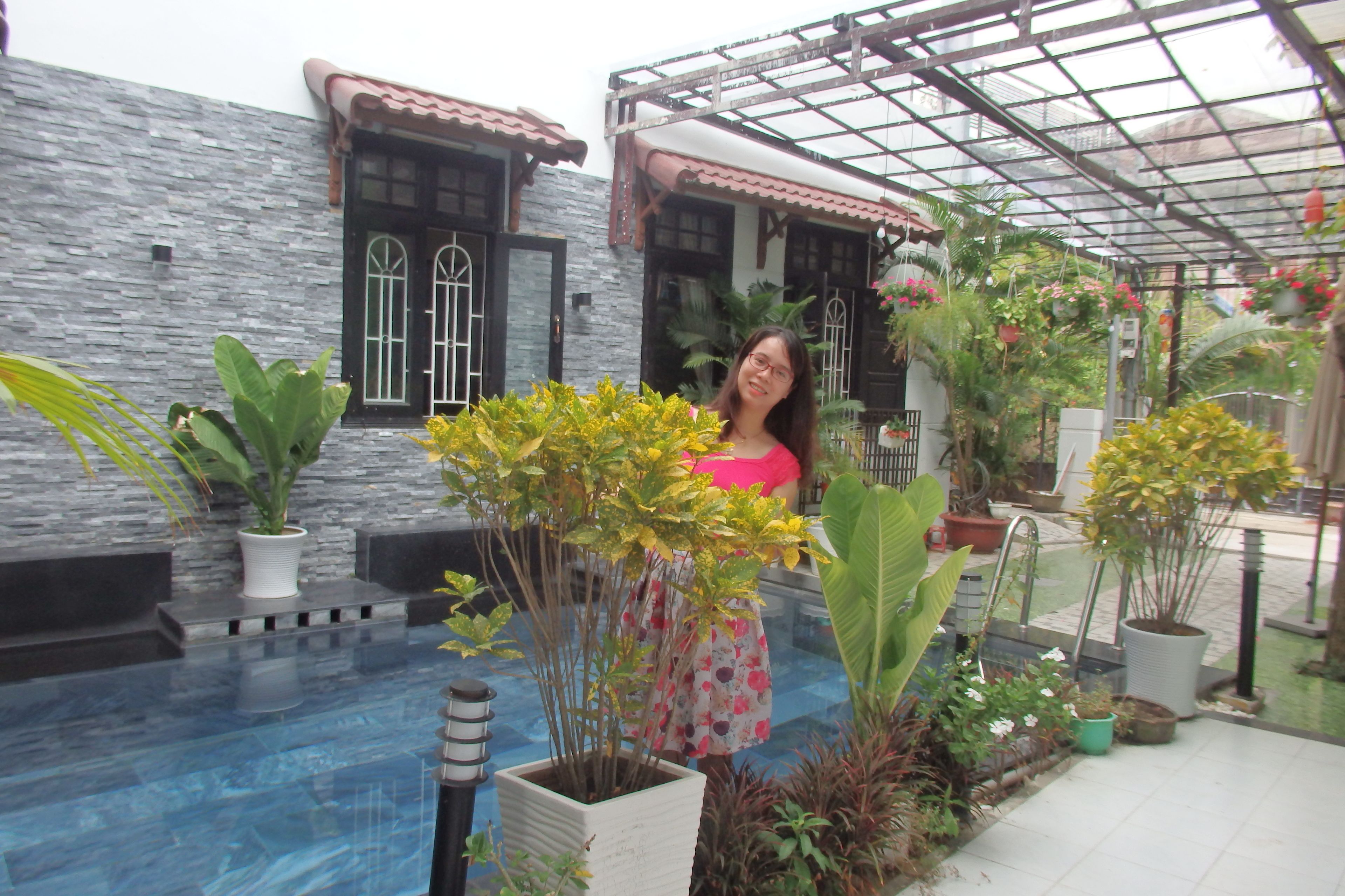 A person standing in a greenhouse with various plants and a water feature.