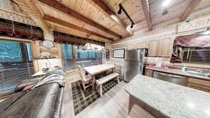 A cabin interior with a wooden dining table, benches, a refrigerator, a sink, and a kitchen counter. - Streamsong Secluded Creek View Cabin with Hot Tub and Pool Table by RedAwning (Sevierville)
