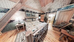 A bedroom with a sloped ceiling, wooden flooring, a bed with a patterned bedspread, a nightstand, a dresser, and a mirror. - Streamsong Secluded Creek View Cabin with Hot Tub and Pool Table by RedAwning (Sevierville)