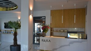 A modern reception area with a marble counter, wooden cabinets, and a potted plant. - Hotel Rajka (Valasske Mezirici)