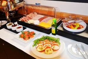 A buffet with various food options including meats, cheeses, and salads.