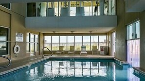 An indoor swimming pool with clear windows, lounge chairs, and a lifebuoy. - Crystal Shores 1104 2 Bedroom Condo by RedAwning (Gulf Shores)
