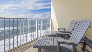 A balcony with two Adirondack chairs and a view of the ocean. - Crystal Shores 1104 2 Bedroom Condo by RedAwning (Gulf Shores)