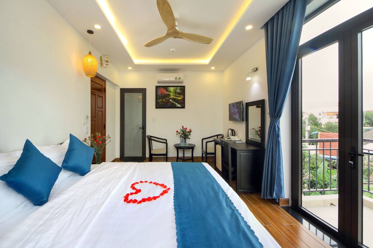 A hotel room with a bed, a desk, and a view of the outside.