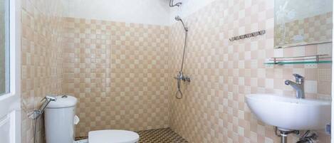 A bathroom with a toilet, a shower, and a sink.