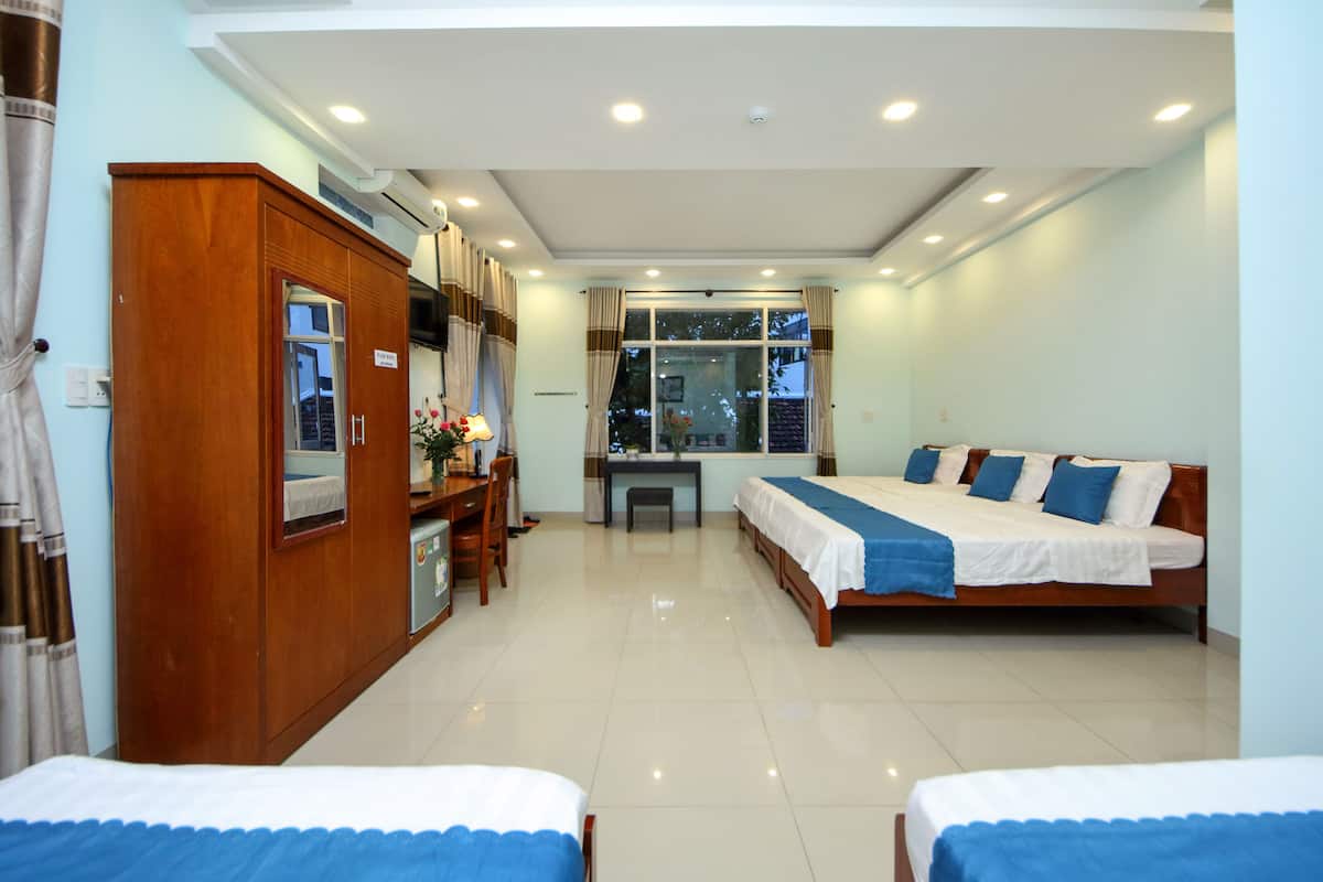 A hotel room with two beds, a desk, and a wardrobe.
