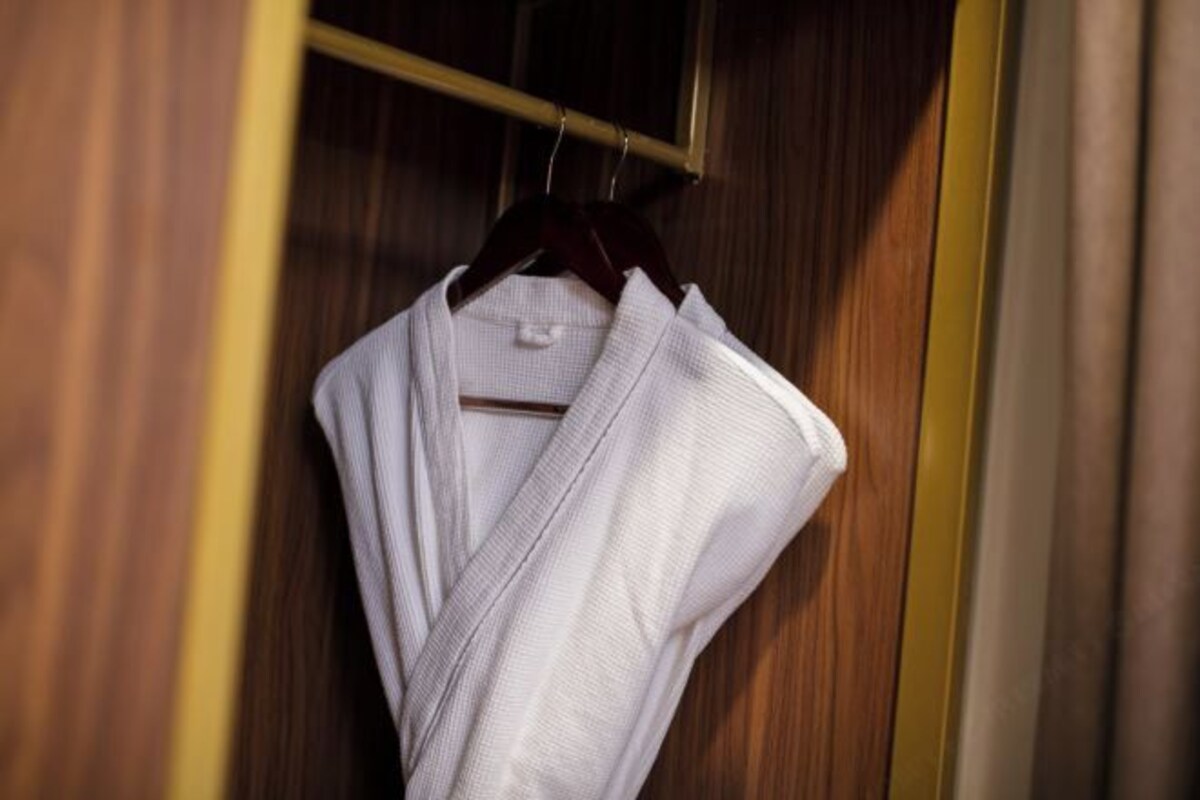 A white garment hanging on a wooden hanger in a wooden closet.