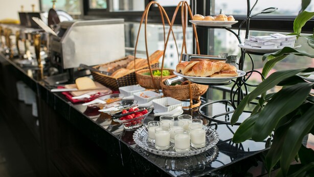 En buffé med ett varierat utbud av mat och dryck, inklusive croissanter, frukt och mjölk.