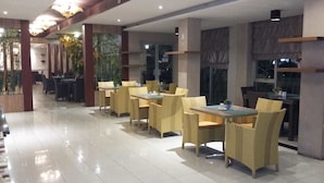 Un restaurante con un interior limpio y moderno, que presenta sillas y mesas de mimbre amarillo, un suelo de baldosas brillantes y un ambiente luminoso y agradable.