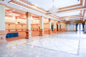Un salón amplio con techos altos, columnas decorativas y candelabros.