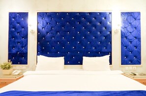 A hotel room with a large bed, a tufted headboard, and a bedside table with a lamp. - Horison Altama Pandeglang (Pandeglang)