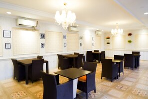 A hotel dining area with multiple tables and chairs, air conditioning units, and decorative wall panels. - Horison Altama Pandeglang (Pandeglang)