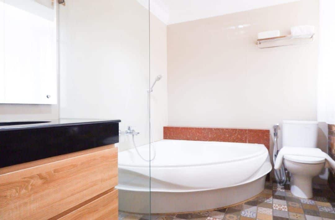 A bathroom with a bathtub, toilet, and a mirror.