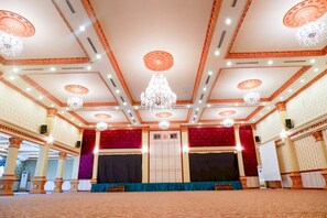 A grand hall with a stage, ornate ceiling, and chandeliers. - Horison Altama Pandeglang (Pandeglang)