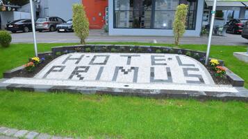 A hotel sign with the name "HOTEL PRIMOS" in a garden setting.