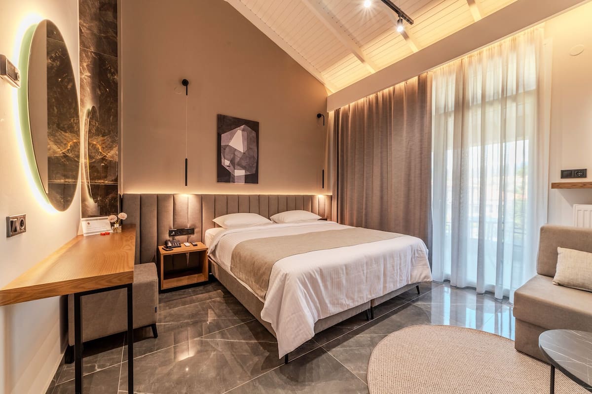A modern hotel room with a large bed, a desk, and a seating area.