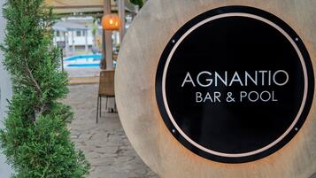 Un letrero para 'AGNANTIO BAR & POOL' con un marco de madera y un fondo circular negro.