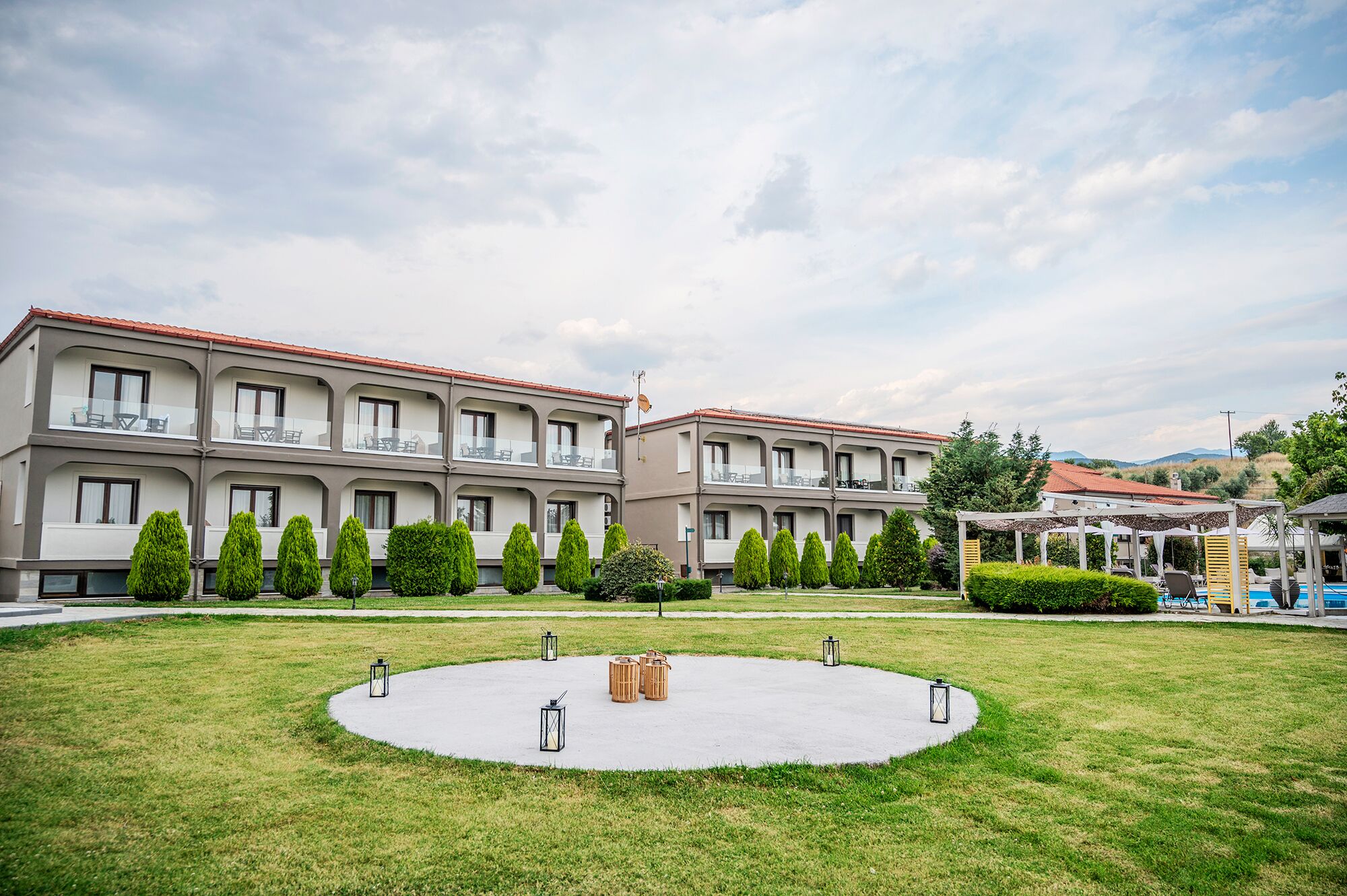 Un hotel con patio que presenta un área circular de concreto con faroles y taburetes de madera.