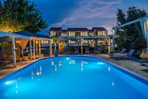Una piscina al aire libre, sombrillas, sillones reclinables de piscina