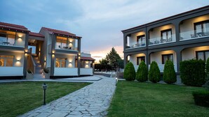 Un hotel moderno con un camino de piedra que lleva a la entrada, varios balcones y un césped cuidado.