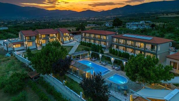 Un resort con varias edificaciones, una piscina y vistas a montañas distantes.
