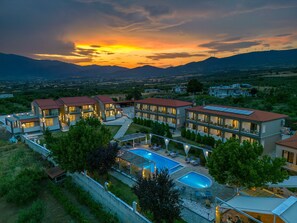 Un resort con varias edificaciones, una piscina y vistas a montañas distantes.