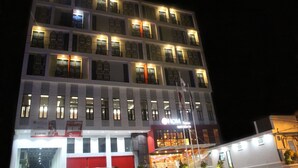 Un hôtel à plusieurs étages, doté de fenêtres illuminées et d’une grande enseigne « HOM » bien visible.