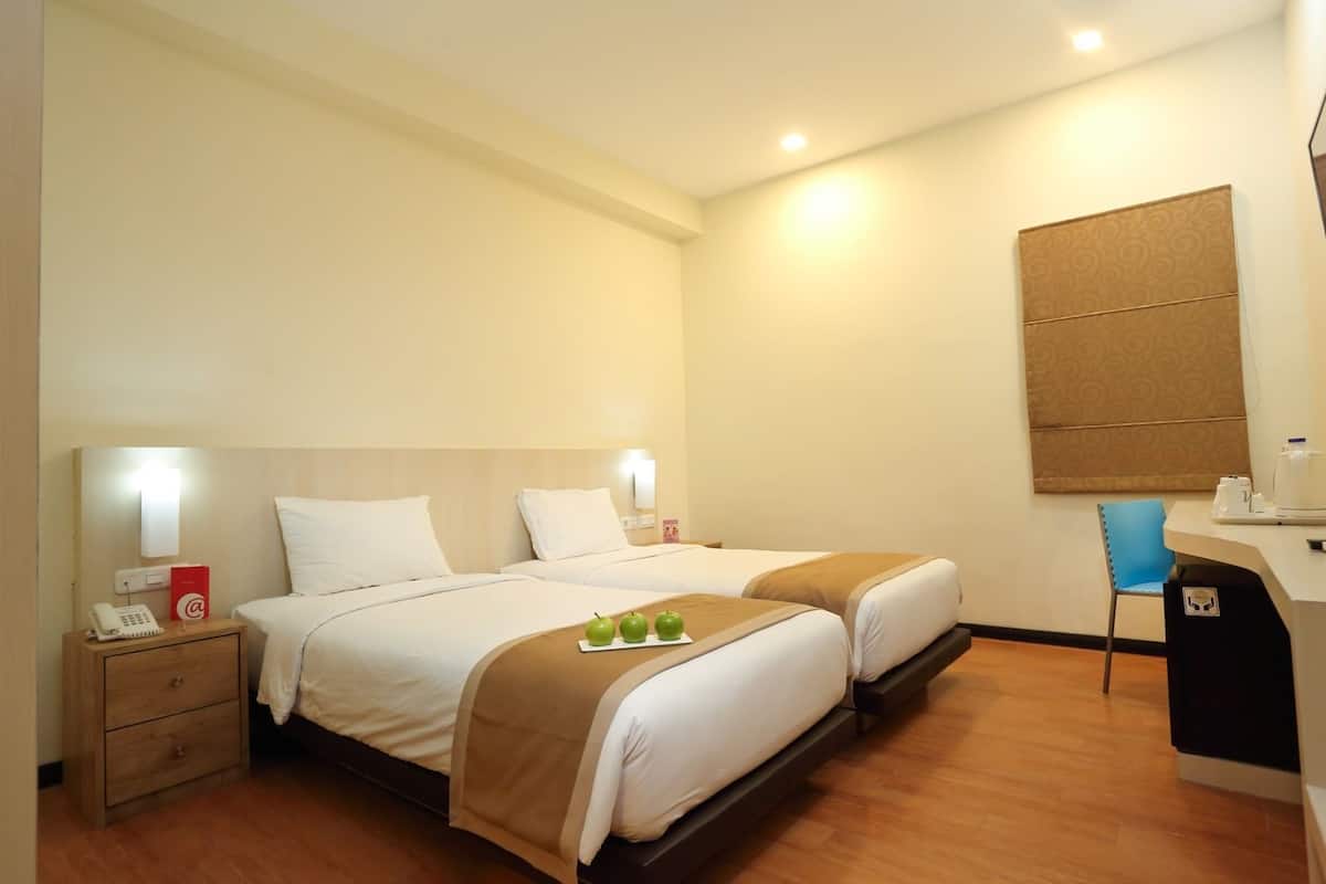Une chambre d’hôtel avec deux lits, un bureau, une chaise et un mini-bar.