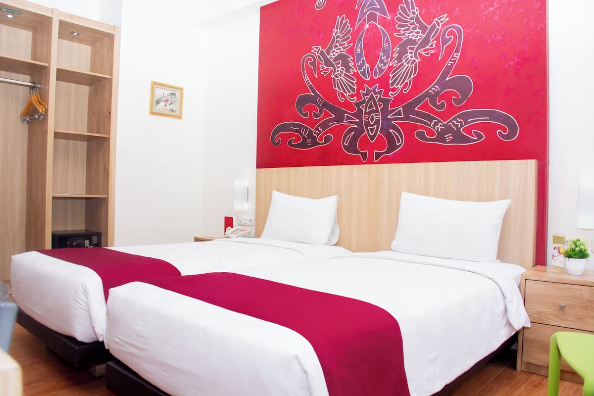 Une chambre d’hôtel avec un grand lit, une armoire en bois et un mur rouge orné d’un motif décoratif.