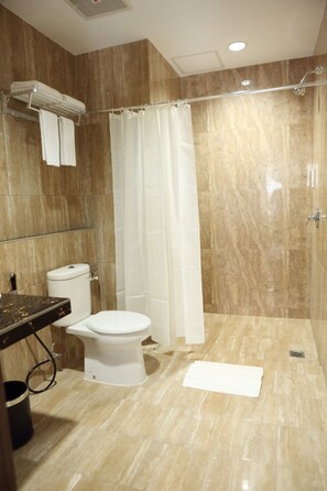 A bathroom with a toilet, a shower, and a towel rack.