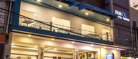 Un hotel con un llamativo letrero 'HOREX', un acceso cubierto y un restaurante visible en su interior.