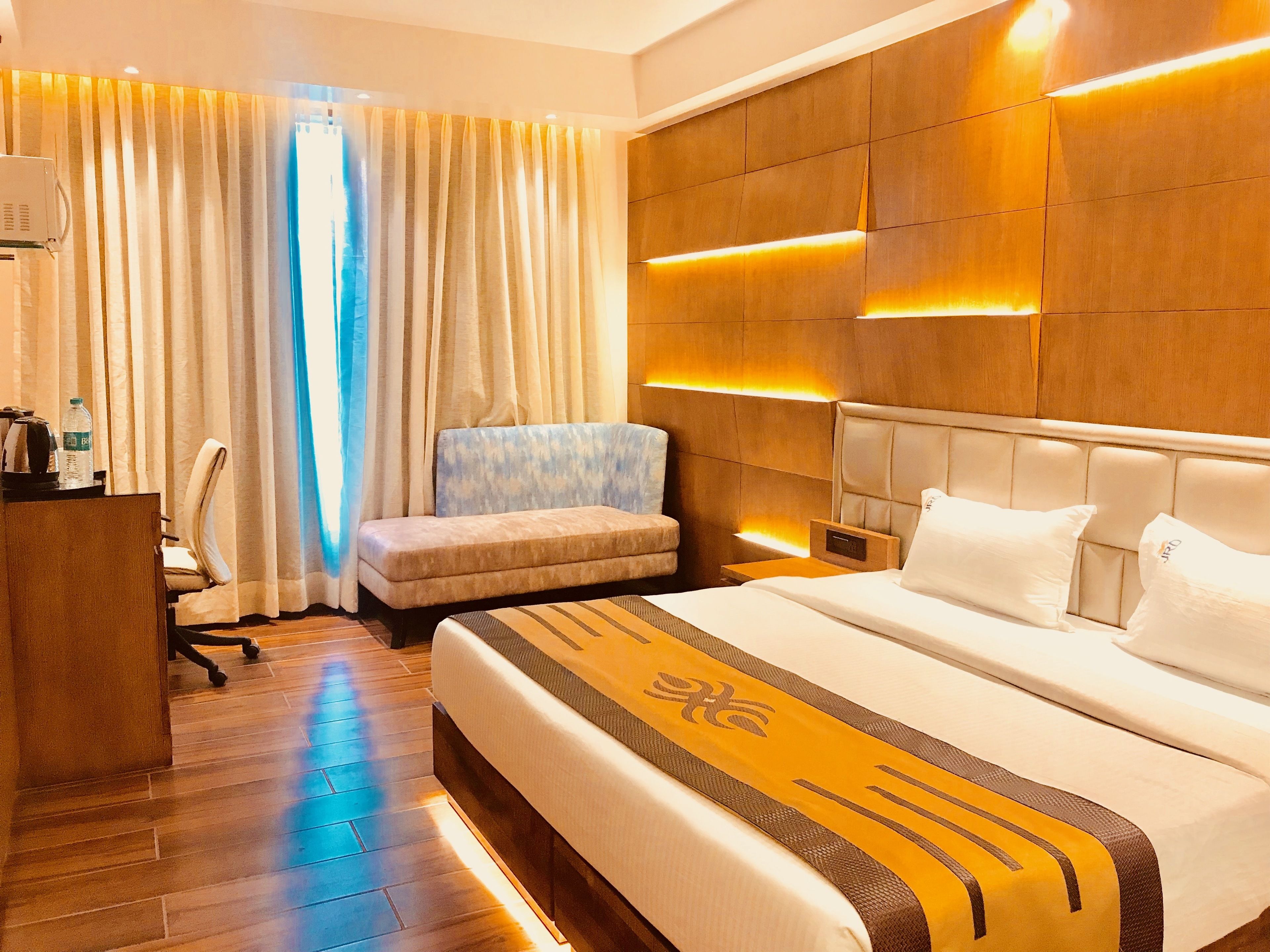 A hotel room with a large bed, a sofa, a desk, and a chair.
