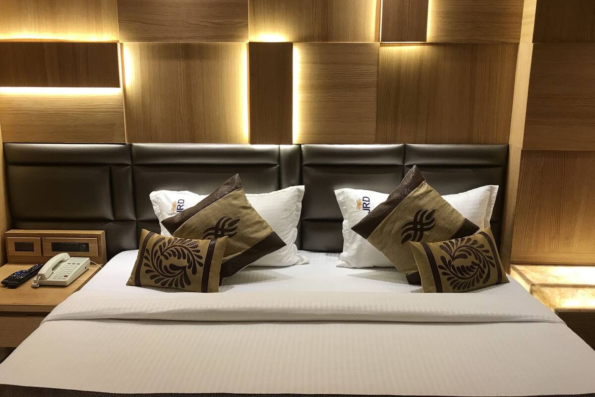 Ein Hotelzimmer mit einem großen Bett, zwei Nachttischen, einem Telefon und einer Wand mit Holzvertäfelung und eingelassener Beleuchtung.