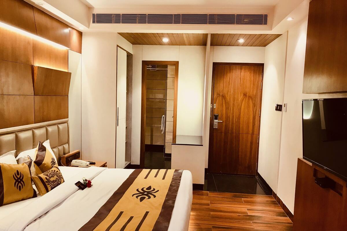 Ein Hotelzimmer mit Bett, Nachttisch, Telefon und Fernseher.