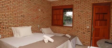 A room with two beds, a window, and a door.