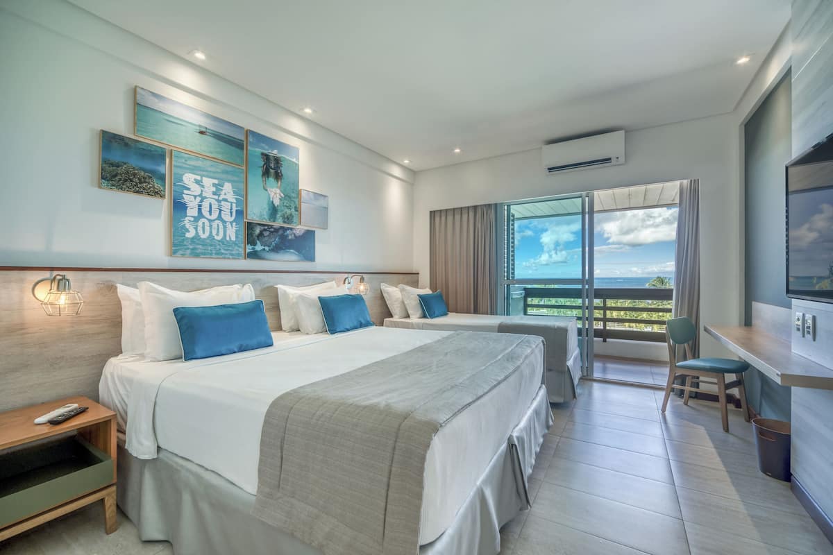 Une chambre d’hôtel moderne avec un grand lit, un bureau et un balcon offrant une vue agréable.