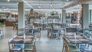 A spacious restaurant with high ceilings, pendant lighting, and a variety of seating arrangements.