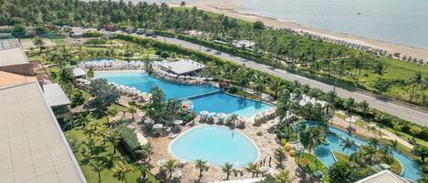 A resort with multiple swimming pools, a beach, and lush greenery.