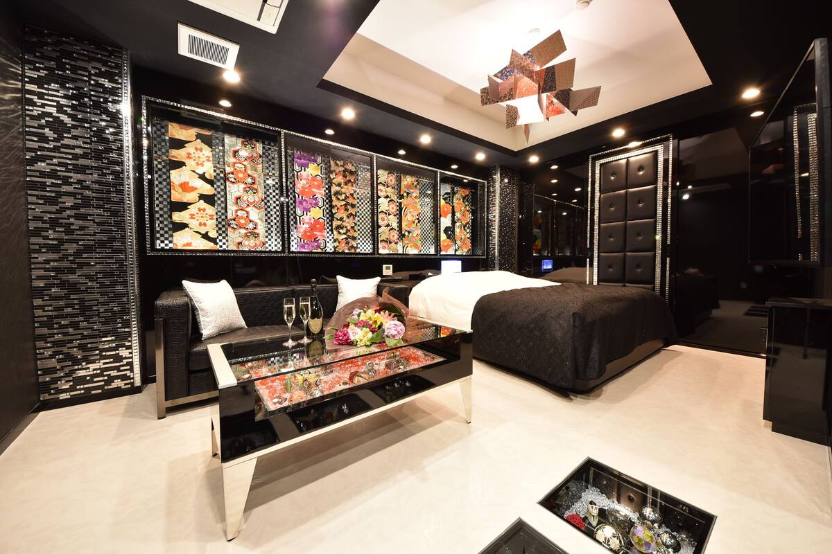 Une chambre d’hôtel moderne dotée d’un grand lit, d’un coin salon avec une table basse en verre et d’un mur décoratif orné d’œuvres d’art à motifs.