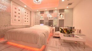 A modern bedroom with a large bed, a glass coffee table, and decorative wall panels. - Hotel SARA Kawagoe - Adults Only (Kawagoe)