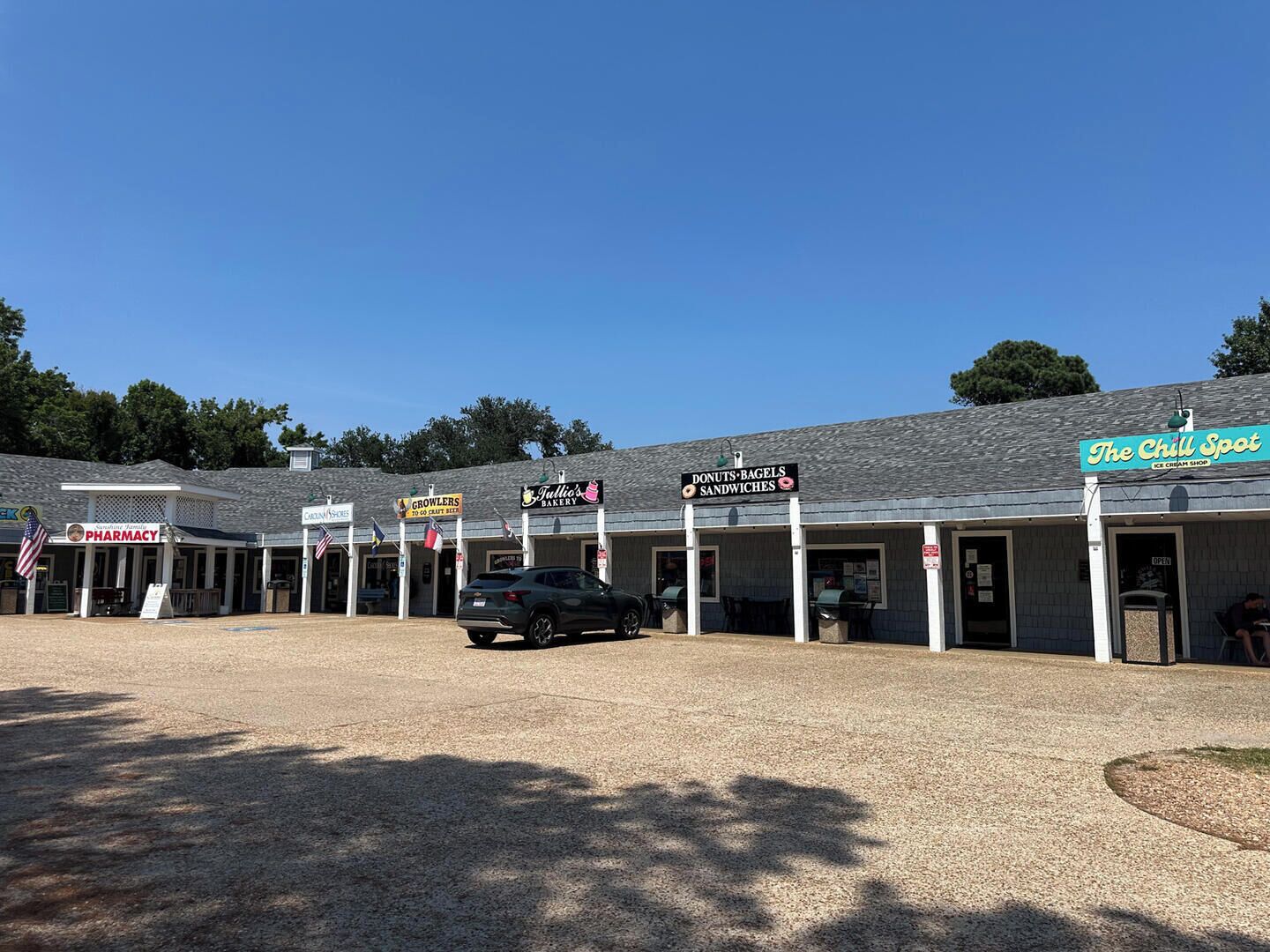A commercial building with multiple storefronts including a pharmacy, bakery, and ice cream shop.