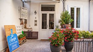 A quaint entrance with a wooden bench, potted plants, and a signboard. - Borgo Vergini Garden (Naples)
