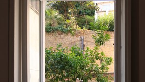 A view through an open door to a balcony with a small tree, potted plants, and outdoor furniture. - Borgo Vergini Garden (Naples)